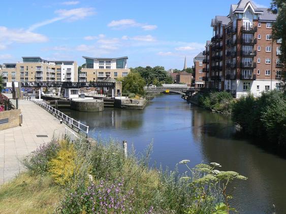 Tranquil view near junction of two waterways with blocks of modern flats overlooking the scene