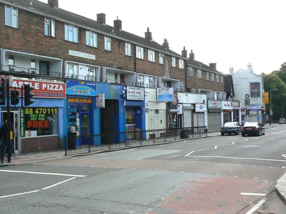 Parade of 1950s 3-storey brick-built shops with acccommodation over